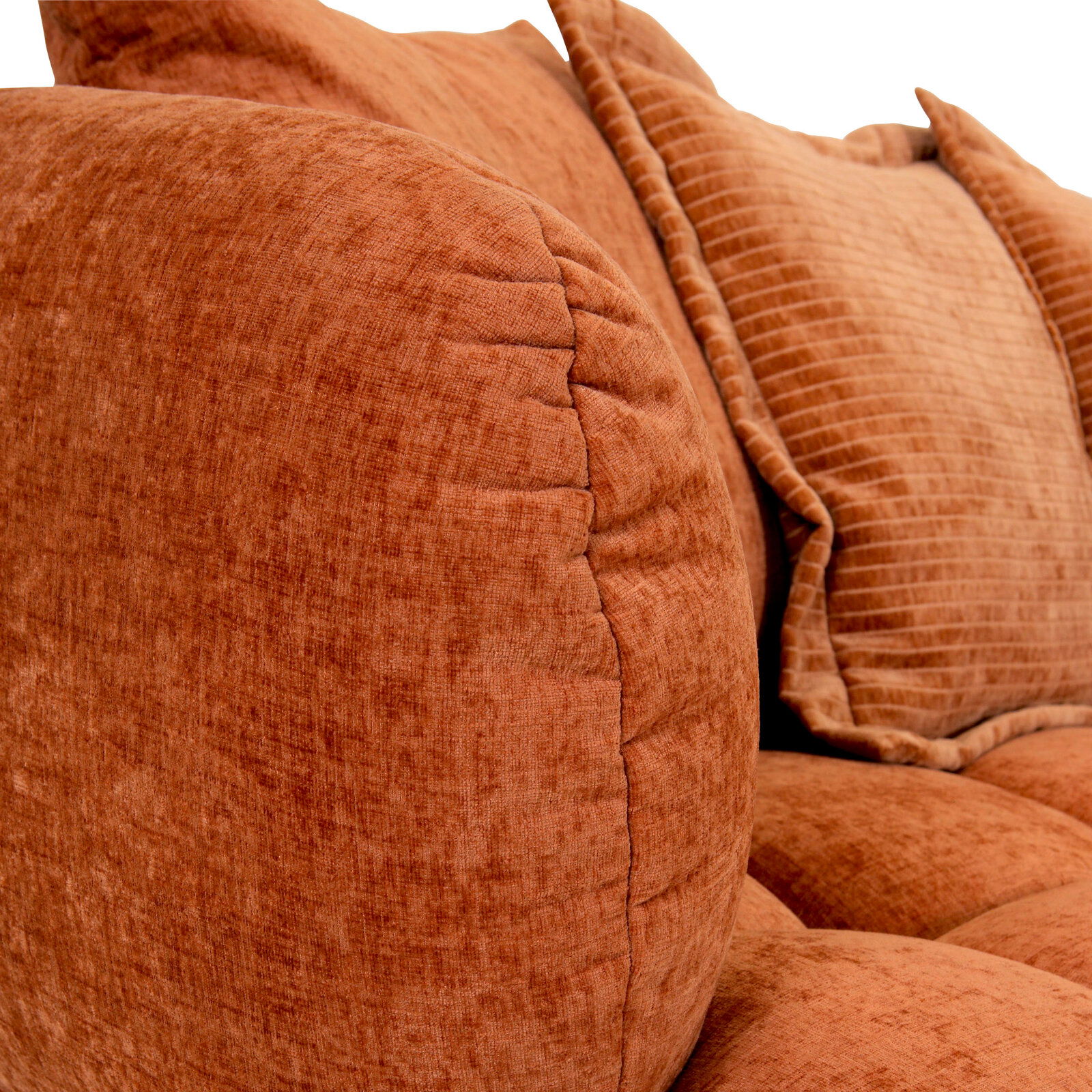 Nahaufnahme eines Big-Sofas in warmem Terrakotta-Ton mit weichen, strukturierten Kissen, seitliche Perspektive.