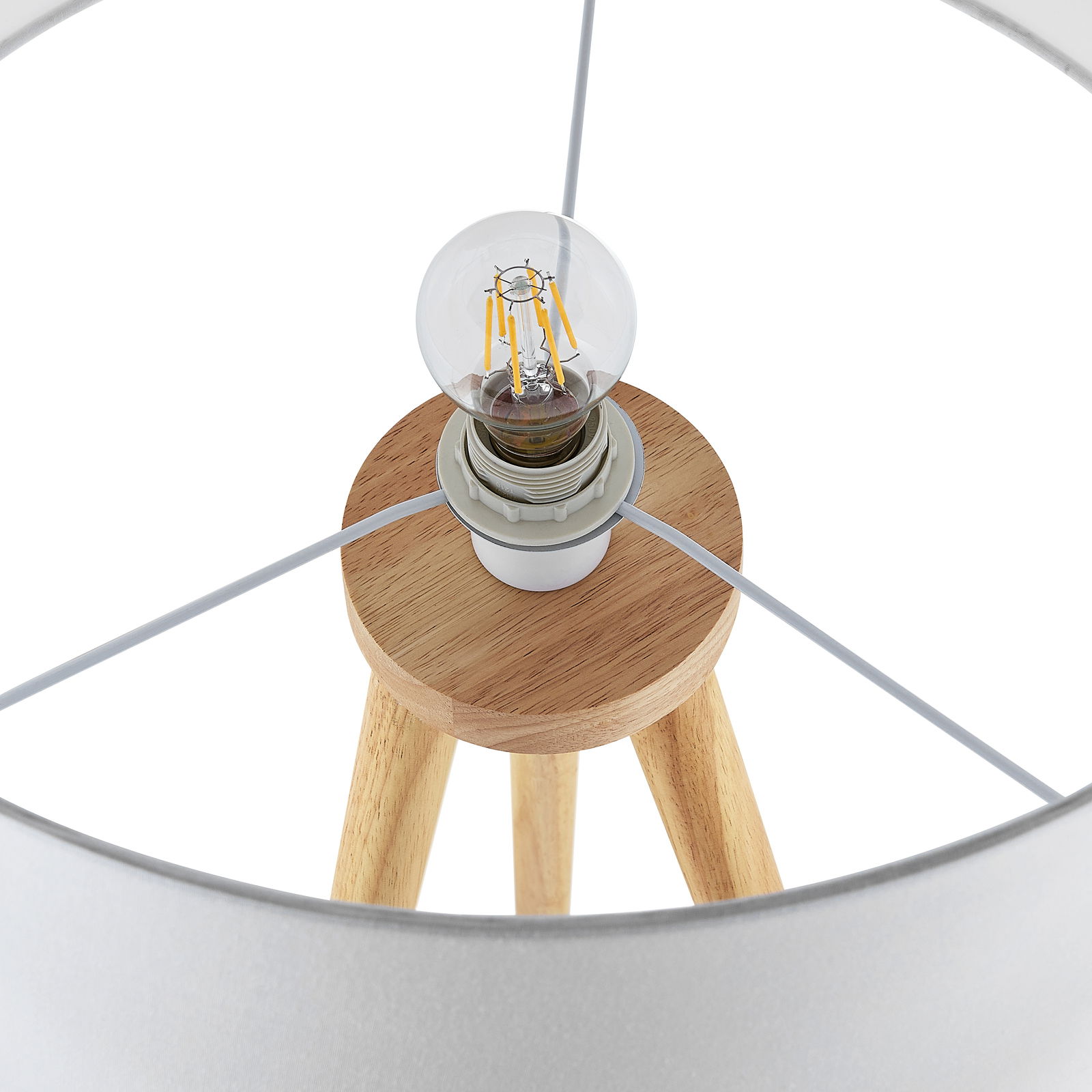 Nahaufnahme einer Stehleuchte mit Holzstativ und sichtbarer Glühbirne von oben betrachtet.