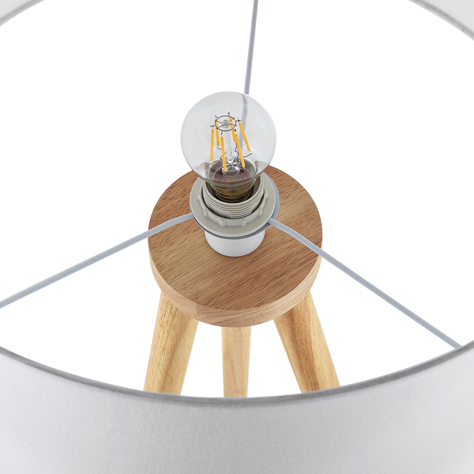 Close-up van een staande lamp met houten voet en zichtbare gloeilamp, gezien van bovenaf.
