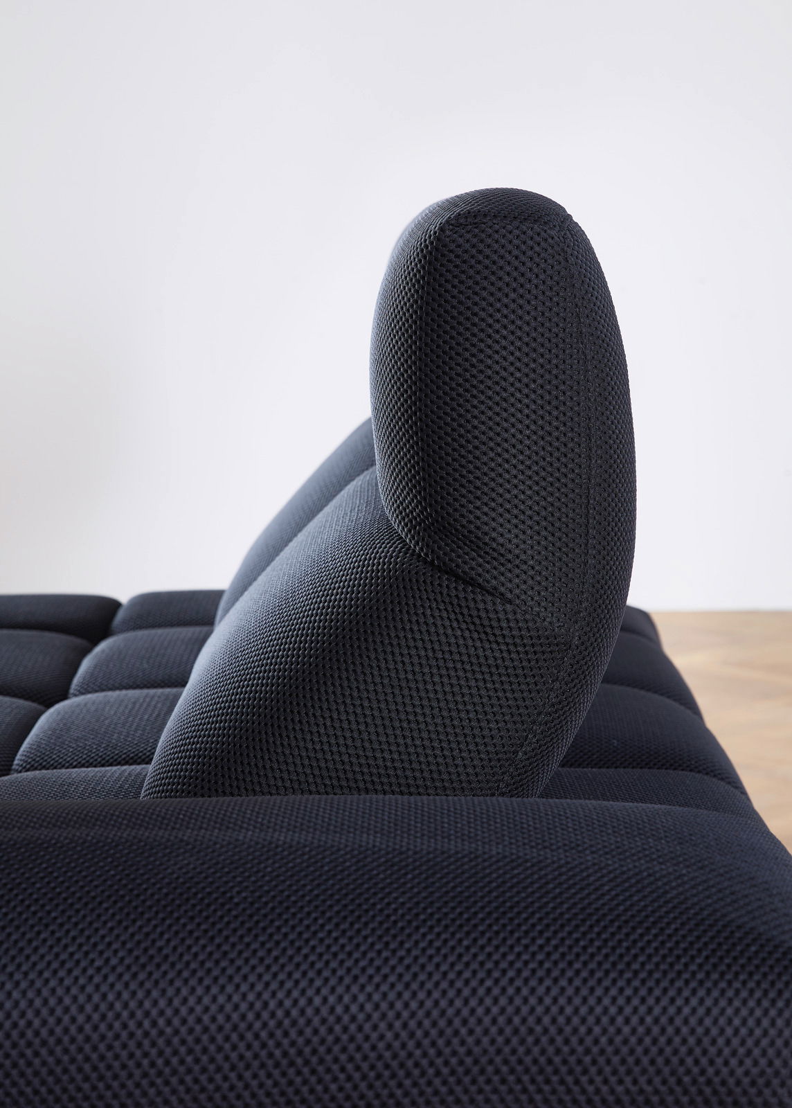 Seitenansicht einer dunkelblauen Eckgarnitur mit strukturierter Oberfläche und gepolsterter Rückenlehne.