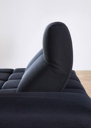 Seitenansicht einer dunkelblauen Eckgarnitur mit strukturierter Oberfläche und gepolsterter Rückenlehne.
