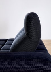 Zijaanzicht van een donkerblauwe hoekbank met een gestructureerd oppervlak en een gestoffeerde rugleuning.