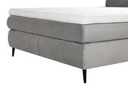 Seitliche Perspektive eines grauen Boxspringbetts mit schwarzem Bein und weißer Matratze.