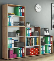 Modulares Büroregal aus Holzoptik mit weißen Einlegeböden, gefüllt mit farbigen Ordnern, Büchern und Aufbewahrungsboxen; Frontansicht leicht schräg von links in einem modernen Arbeitszimmer