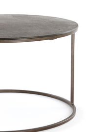 Nahaufnahme eines runden Couchtisches mit Metallrahmen und dunkler Tischplatte, seitliche Perspektive.