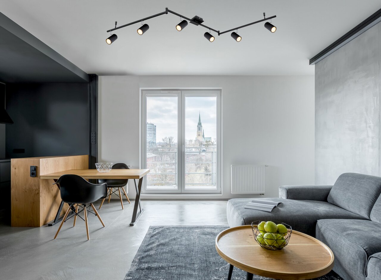 Moderne zwarte plafondspot met zes verstelbare spots in een stijlvolle woonkamer, gezien vanaf de zijkant.