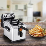 Fritteuse Filtra Pro Inox von schräg vorne auf einem Holztisch in einer Küche, neben einem Teller mit Pommes frites.
