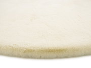 Nahaufnahme eines cremefarbenen Fellteppichs mit weicher, flauschiger Textur.