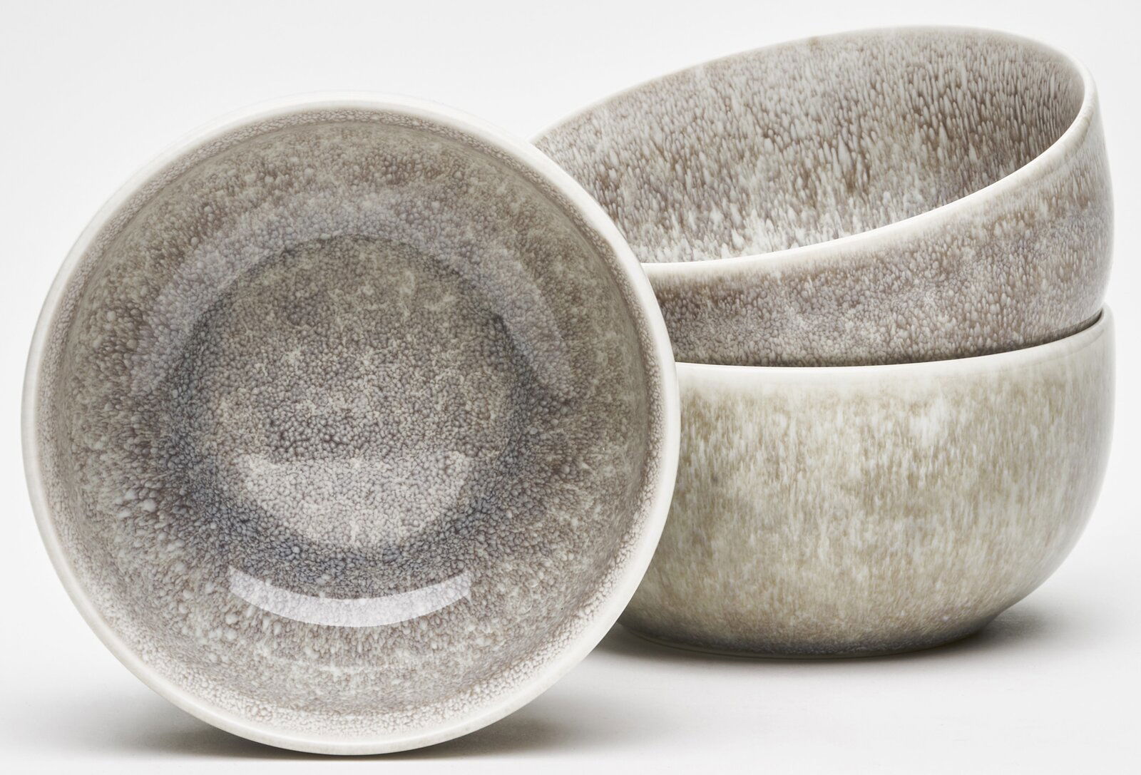 Set aus vier Schalen mit natürlichem, gesprenkeltem Design in Erdtönen, eine Schale in Nahaufnahme von oben, die anderen gestapelt.