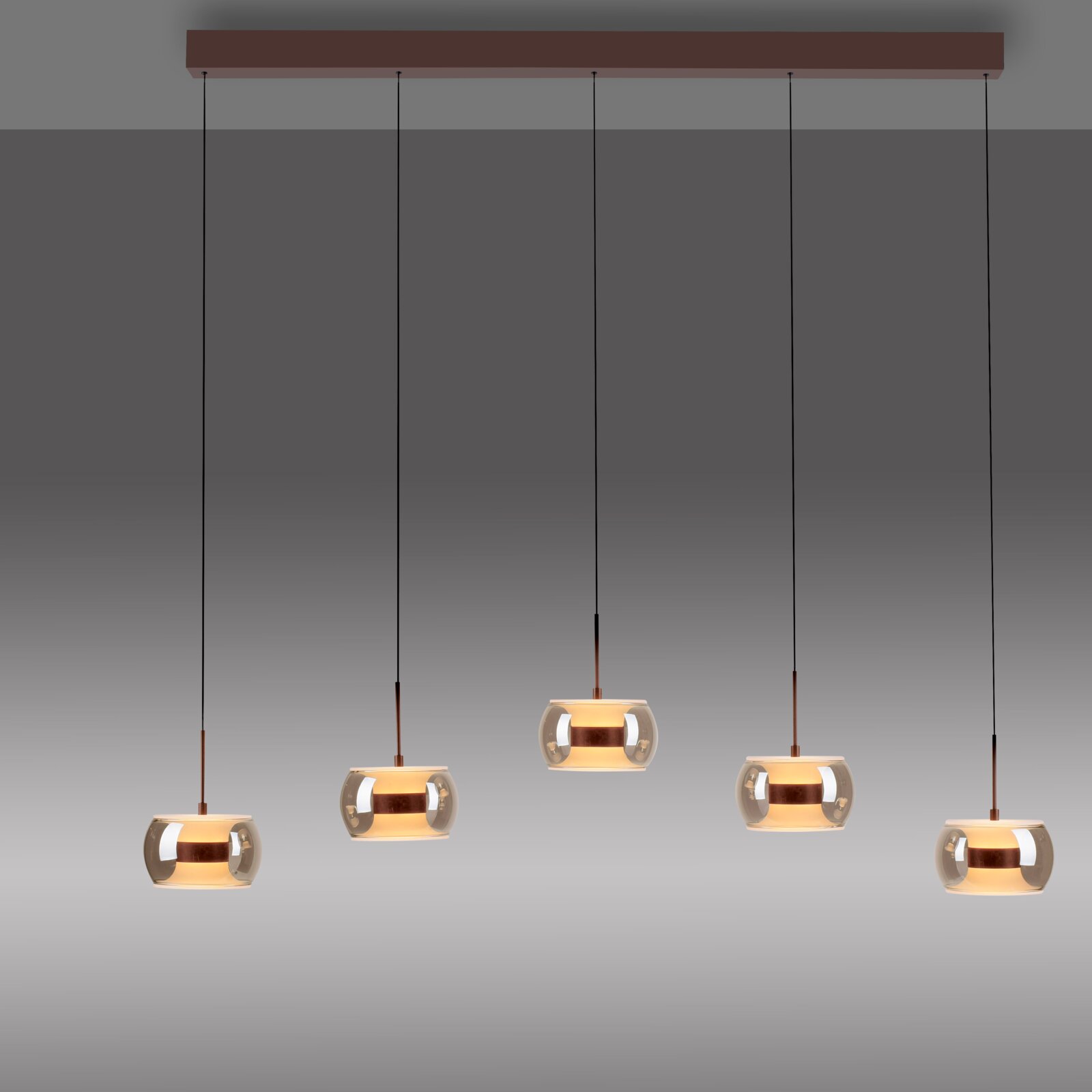 Moderne 4-flammige Pendelleuchte mit rauchgrauen Glas-Schirmen und kupferfarbenen Details an einer länglichen Deckenleiste, warm leuchtend, Frontalansicht