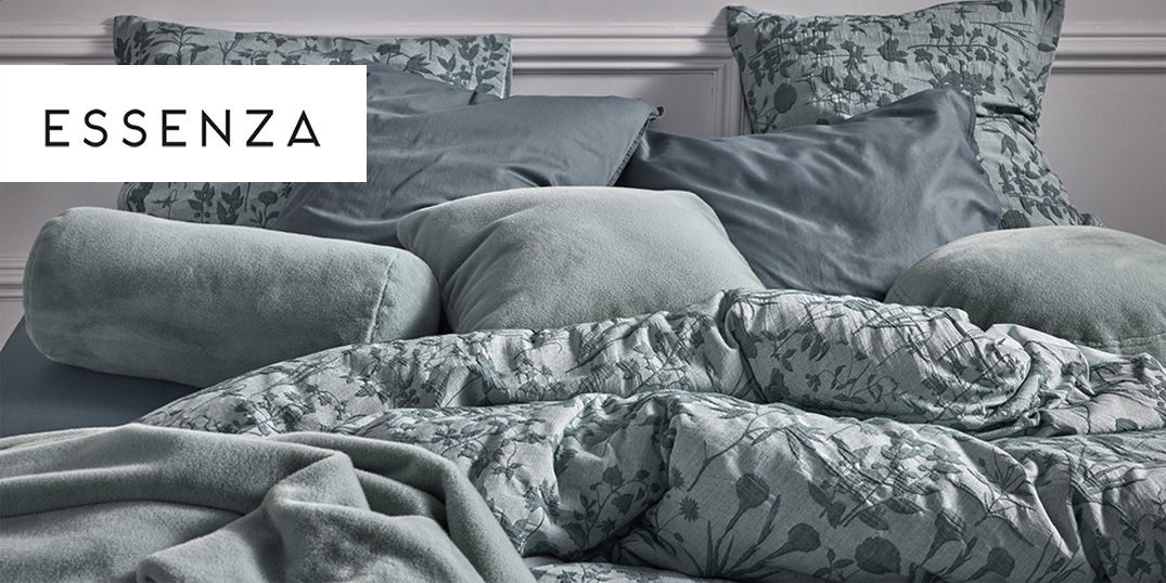 Ein gemütliches Bett mit vielen weichen Kissen und grüner Bettwäsche mit Blumenmuster.