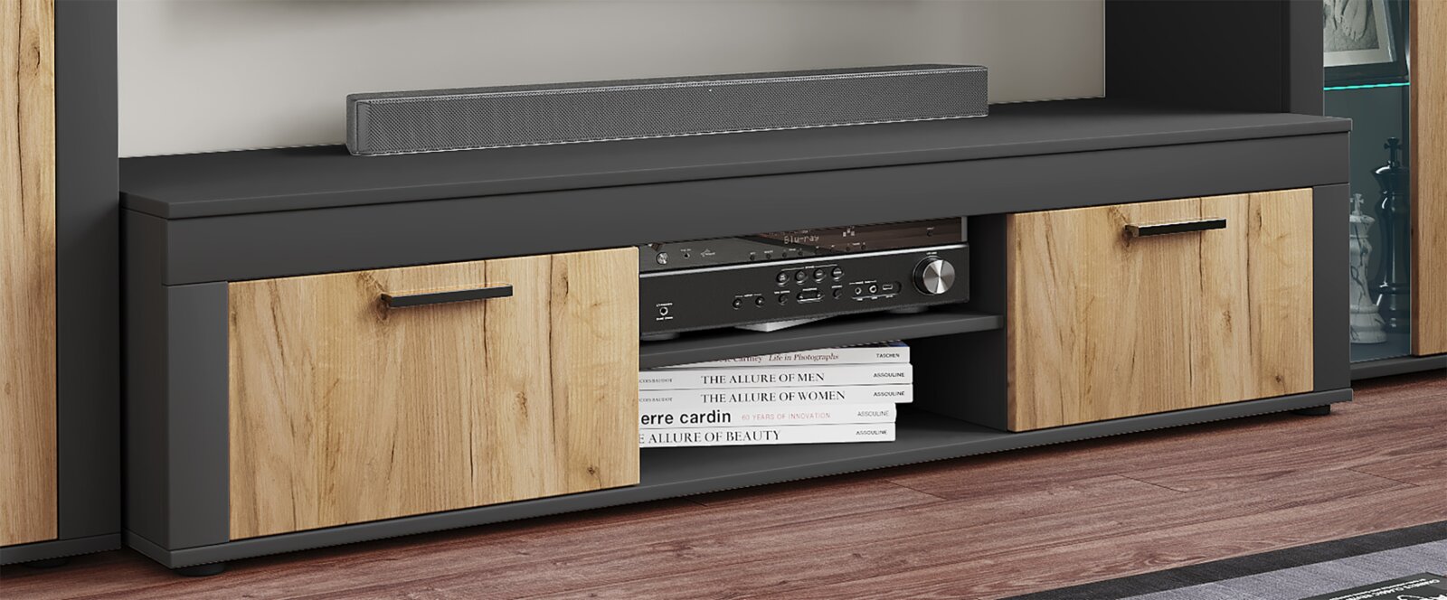 Modernes TV-Lowboard in Schwarz mit zwei Holzfront-Türen und offenen Fächern, mit Soundbar oben und Receiver sowie Büchern im Fach, gezeigt in frontaler Perspektive auf Augenhöhe.