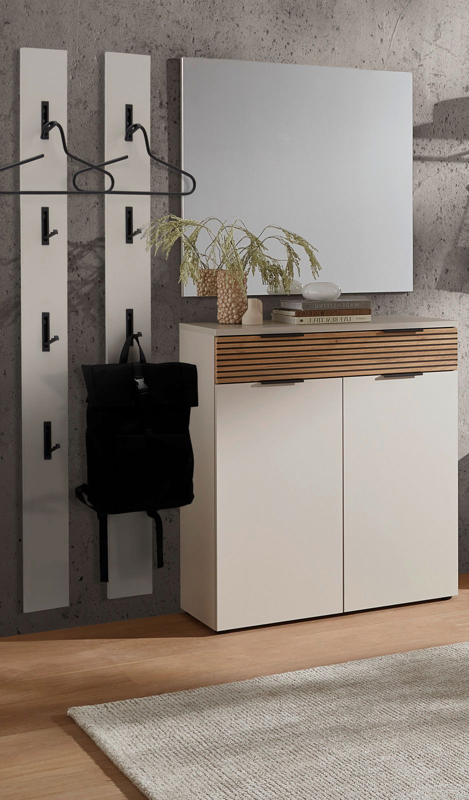 Voleo Garderoben-Set INDO Garderoben-Set mit zwei vertikalen Paneelen mit Haken, einem weißen Schrank mit Holzdetails und einem großen Spiegel, aus der Perspektive von vorne betrachtet.