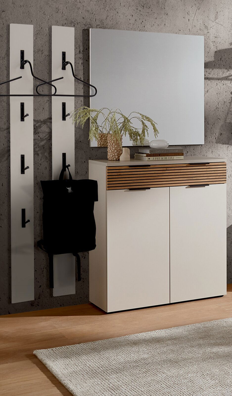 Garderoben-Set mit zwei vertikalen Paneelen mit Haken, einem weißen Schrank mit Holzdetails und einem großen Spiegel, aus der Perspektive von vorne betrachtet.