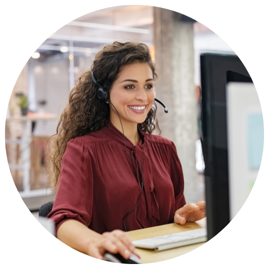 Frau sitzt vor einem Bildschirm und hat ein Headset auf. 