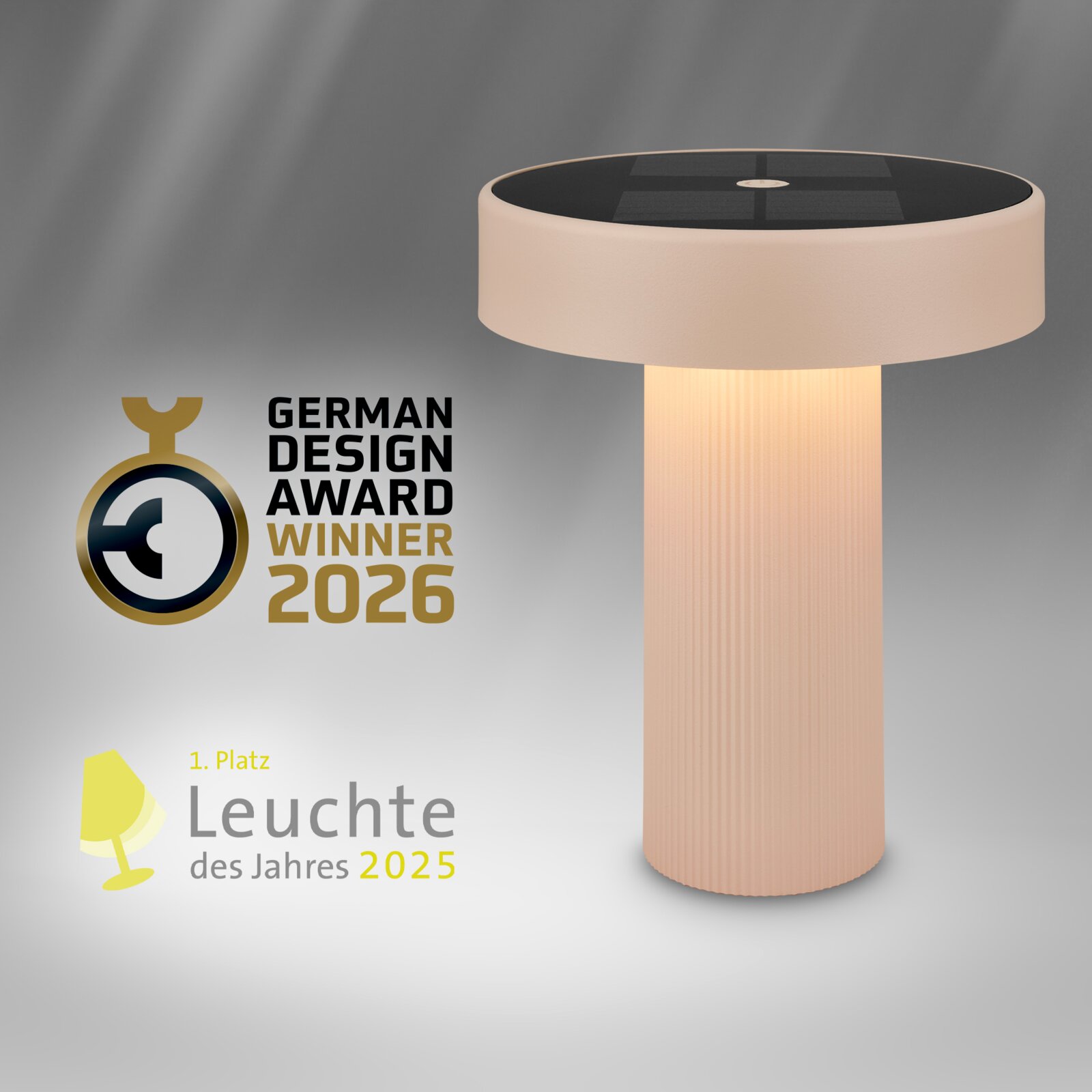 Leuchtende Tischlampe mit zylindrischem, geriffeltem Fuß und rundem, hellem Lampenschirm mit dunkler Oberseite, in schräger Seitenansicht von oben vor grauem Hintergrund; daneben Logos „German Design Award Winner 2026“ und „Leuchte des Jahres 2025“.