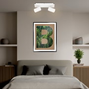 Zweiflammiger LED-Spot in modernem Design, an der Decke über einem stilvoll eingerichteten Schlafzimmer montiert, mit Blick von vorne.