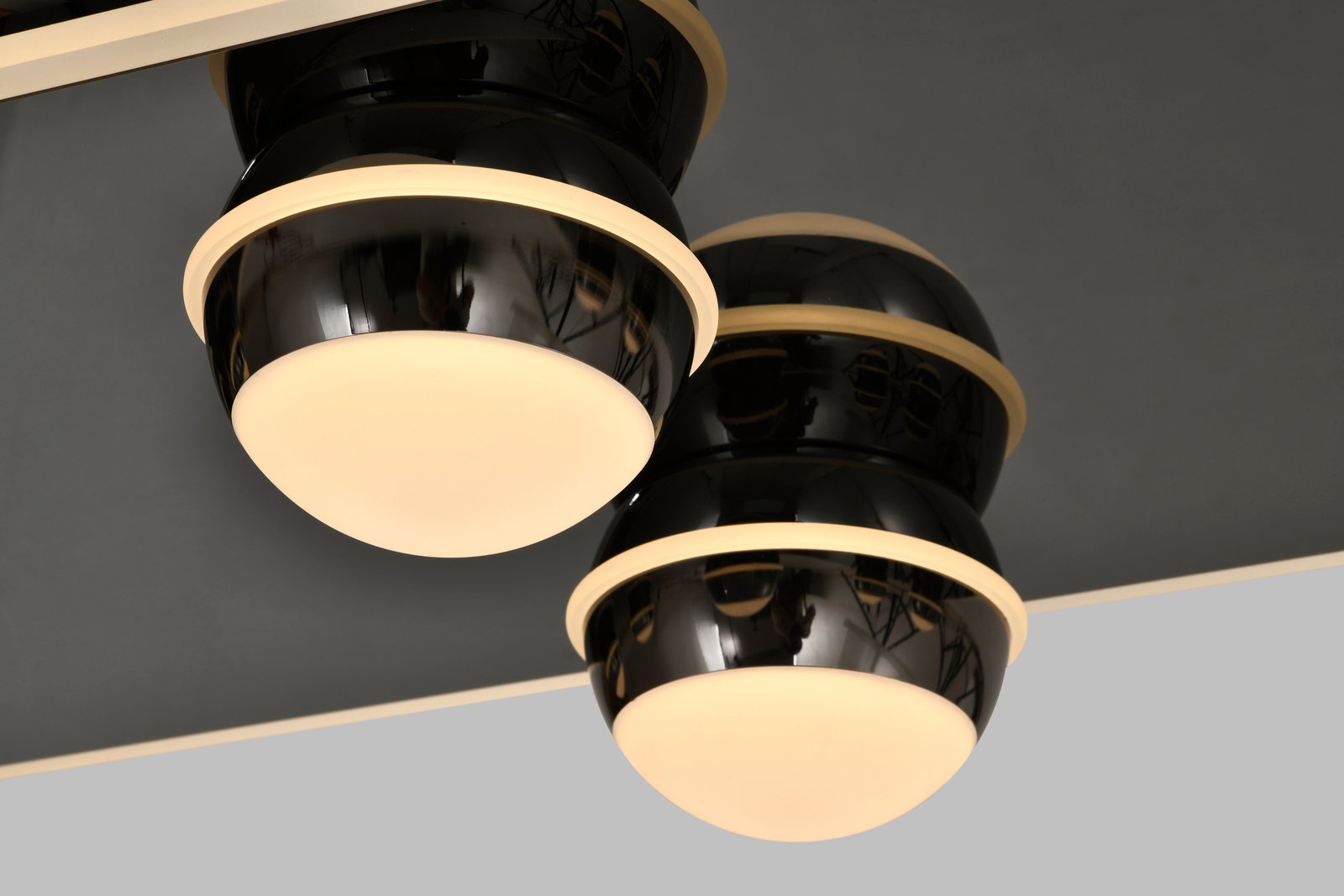 Zwei moderne LED-Deckenleuchten mit schwarzem Gehäuse und warmweißer Lichtabstrahlung, von unten betrachtet.