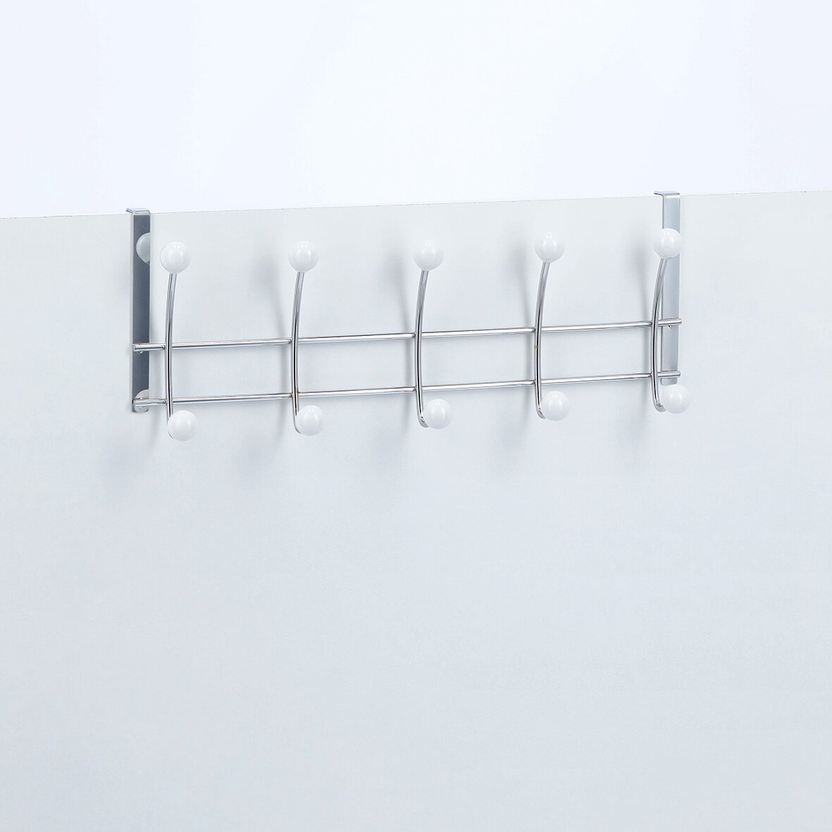 Türhängeleiste mit fünf Haken, aus Metall mit weißen Kugelenden, frontal an einer Tür montiert.