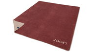 Rote JOOP! Decke mit beiger Rückseite, ausgebreitet auf einer Fläche, mit sichtbarem Markenlogo in der Ecke.