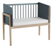 Anstellbett aus Holz mit blauen Seitenteilen und weißer Matratze, seitliche Perspektive