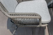 Nahaufnahme eines Armlehnstuhls mit grauem Geflecht und gepolstertem Sitz, seitliche Perspektive