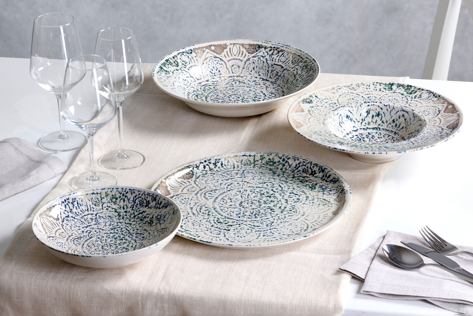 Ritzenhoff & Breker Pizzateller LUIGI Pizzateller 30 cm Luigi mit kunstvollem Muster in Draufsicht, umgeben von weiteren Geschirrteilen und Weingläsern auf einem gedeckten Tisch.