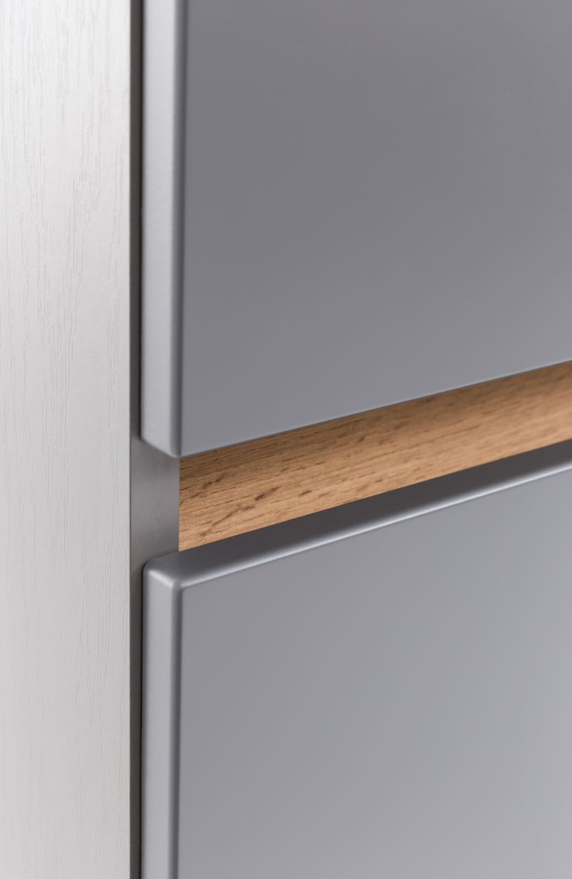 Nahaufnahme eines Unterschranks mit grauer Front und Holzgriff, seitliche Perspektive