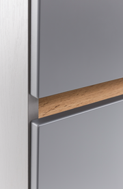 Nahaufnahme eines Unterschranks mit grauer Front und Holzgriff, seitliche Perspektive