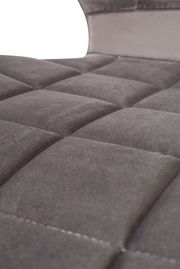 Nahaufnahme eines grauen, gepolsterten Stuhlsitzes mit quadratischem Muster, von der Seite betrachtet.