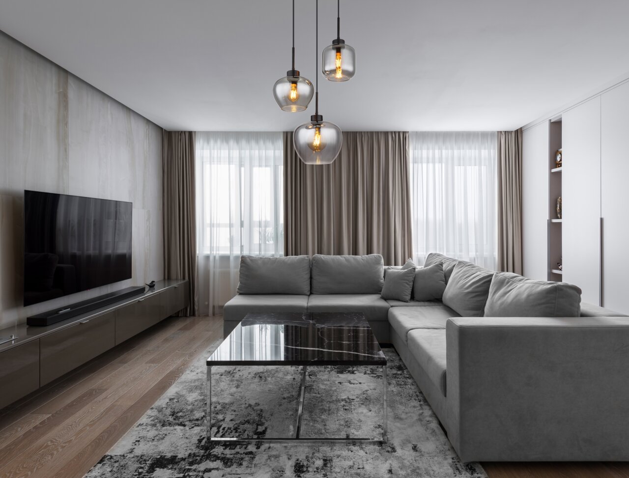 Moderne Hängeleuchte mit drei Glaskugeln in einem stilvollen Wohnzimmer, seitliche Perspektive.