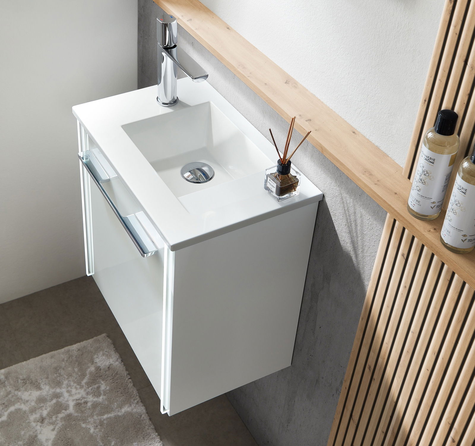 Modernes weißes Waschbecken mit integriertem Unterschrank, von oben fotografiert, mit stilvollem Wasserhahn und dekorativen Elementen.