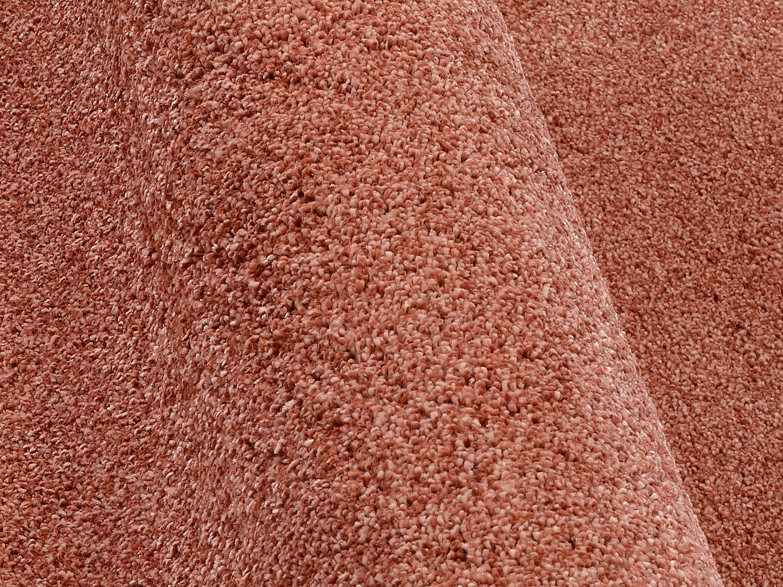 Nahaufnahme eines Uni-Teppichs in warmem Rotton, seitliche Perspektive