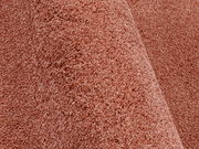 Nahaufnahme eines Uni-Teppichs in warmem Rotton, seitliche Perspektive