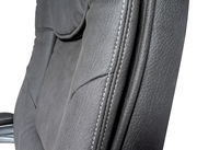 Nahaufnahme eines grauen Chefsessels mit sichtbaren Nähten und Textur, seitliche Perspektive