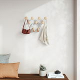 Wandgarderobe mit runden Holzhaken, an der Taschen, Kopfhörer und ein Beutel hängen, seitliche Perspektive