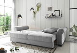 Graues Funktionssofa MAUREEN in einem modernen Wohnzimmer, seitliche Perspektive, mit Kissen und dekorativen Elementen.
