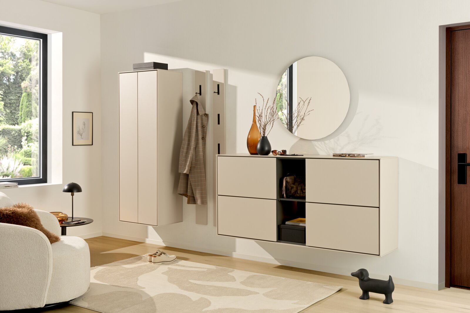 Voleo Garderobeset RENO Moderne, aan de muur bevestigde halmeubelset in beige, bestaande uit een hangkast, een kapstokpaneel met haken, een dressoir en een ronde wandspiegel, hier afgebeeld in een licht schuin vooraanzicht.