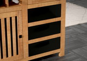 Nahaufnahme eines Highboards mit drei schwarzen Schubladen und einer Holztür mit vertikalen Lamellen, seitliche Perspektive