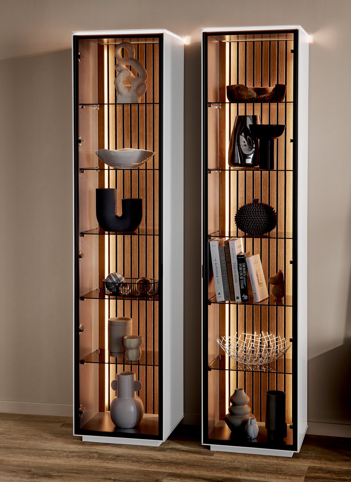 Zwei moderne Vitrinen mit Glasregalen und dekorativen Objekten, frontal betrachtet, mit integrierter Beleuchtung.