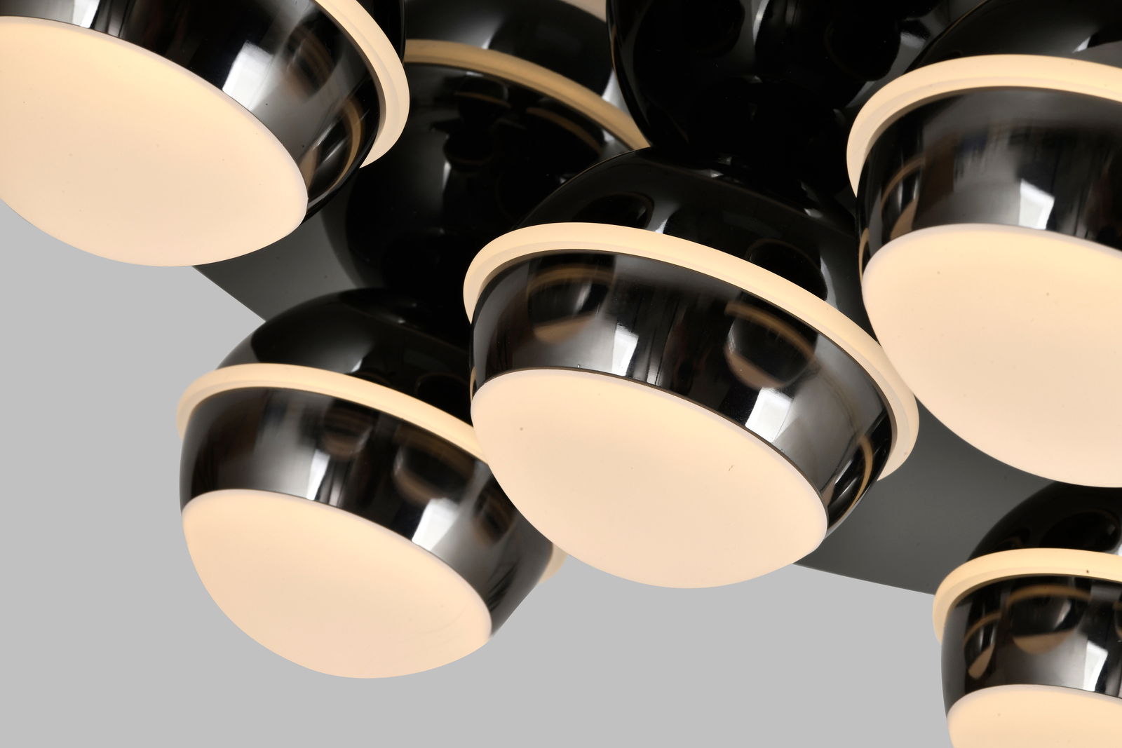 Nahaufnahme einer modernen LED-Deckenleuchte mit mehreren runden, schwarz glänzenden Lampenschirmen und warmweißen Lichtquellen, von unten betrachtet.