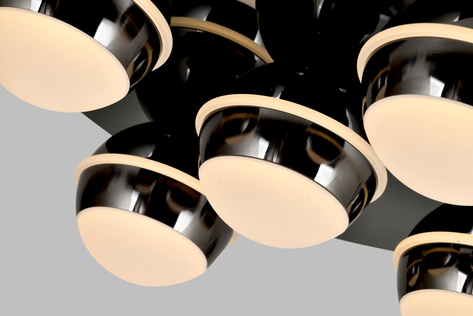 Close-up van een moderne led-plafondlamp met meerdere ronde, glanzend zwarte lampenkappen en warmwitte lichtbronnen, gezien van onderaf.