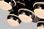 Close-up van een moderne led-plafondlamp met meerdere ronde, glanzend zwarte lampenkappen en warmwitte lichtbronnen, gezien van onderaf.