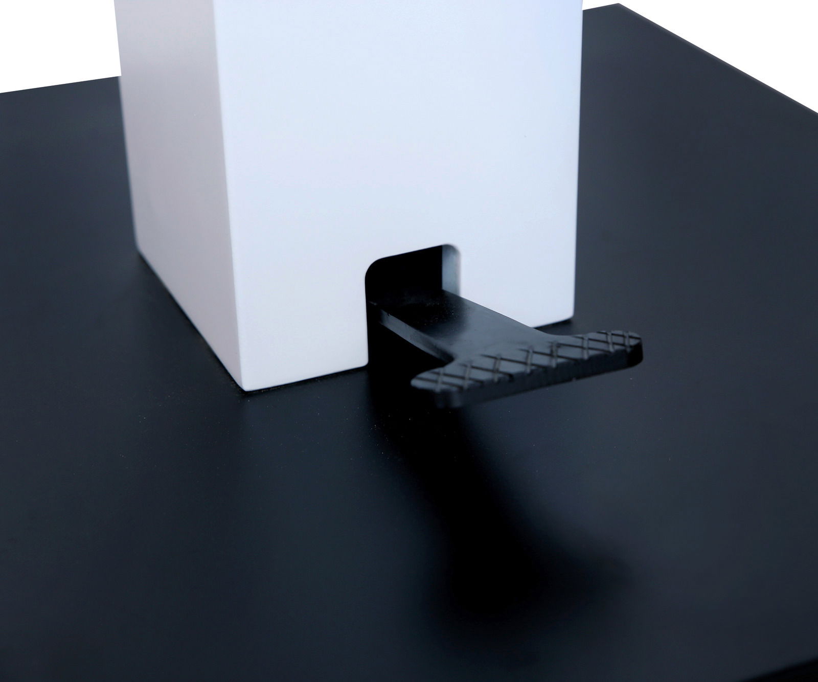 Nahaufnahme eines Couchtischs mit schwarzer Oberfläche und weißem quadratischen Element, seitliche Perspektive.