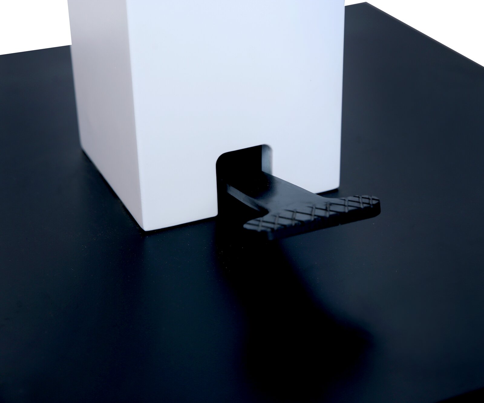 Nahaufnahme eines Couchtischs mit schwarzer Oberfläche und weißem quadratischen Element, seitliche Perspektive.