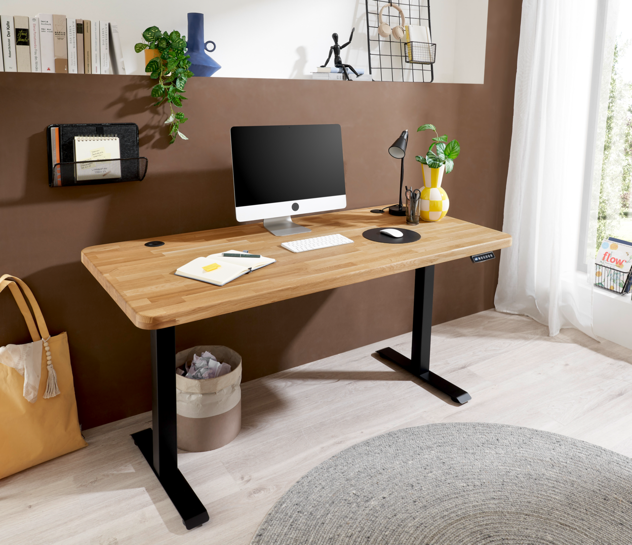 Moderner E-Schreibtisch mit Holzplatte und schwarzem Gestell, ausgestattet mit Computer, Lampe und Pflanzen, seitliche Perspektive.