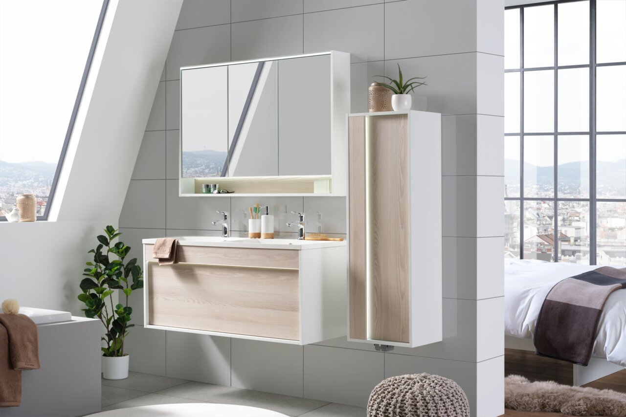 Moderner Waschplatz in einem stilvollen Badezimmer mit großem Fenster, das viel Tageslicht hereinlässt. Der Waschplatz besteht aus einem Doppelwaschbecken mit Holzfront und einem großen Spiegel darüber. Perspektive: Frontalansicht.