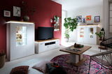 Moderne Wohnkombination mit weißem Schrank und TV-Möbel, dekoriert mit Pflanzen und Kunstwerken, aus der Perspektive des Wohnzimmers.