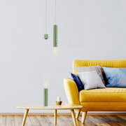 Moderne groene hanglamp op accu in een stijlvolle woonkamer met een gele bank en een houten tafel, zijaanzicht