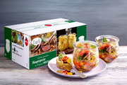 Set aus sechs 370ml WECK-Gläsern für Hauptspeisen, präsentiert mit einem Gericht in einem Glas und einer dekorativen Verpackung im Hintergrund, aus seitlicher Perspektive.